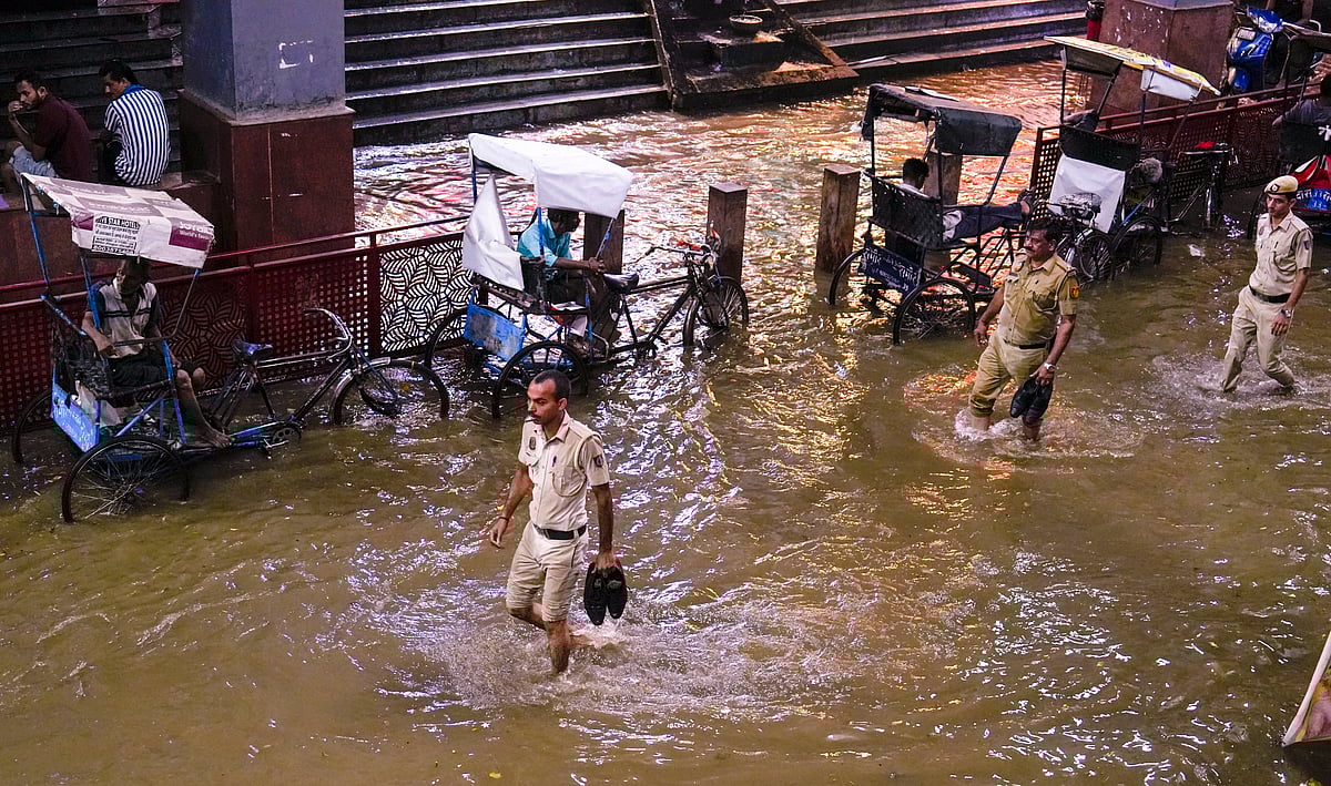 Police personnel wade through a waterlogged road at Karol Bagh metro station during rain, in New Delhi, Wednesday, July 31, 2024.  - PTI